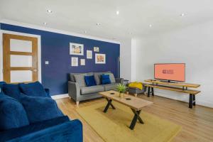a living room with a blue couch and a tv at GuestReady - Charming Retreat in Trafford in Manchester
