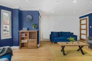 a living room with blue walls and a blue couch at GuestReady - Charming Retreat in Trafford in Manchester +35 photos