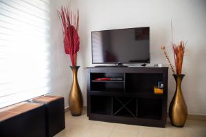 three vases sitting on a entertainment center with a television at La casa de Yaya in Puerto Escondido