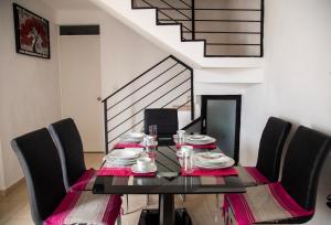 a dining room with a table with chairs and a staircase at La casa de Yaya in Puerto Escondido