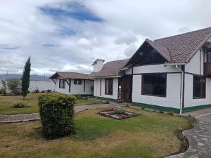 a white house with a yard with a house at Beautiful country house in Latacunga in Pujilí