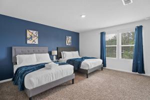 a bedroom with two beds and a blue wall at Charming 3BR Townhome. in Deerwood Club