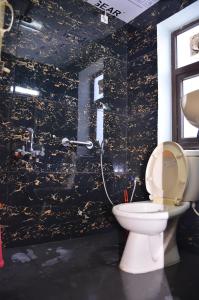 a bathroom with a toilet and a black wall at ARYASREE homestay in Kodaikānāl +20 photos