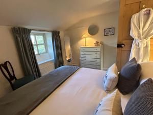 Un dormitorio con una cama y una cómoda y una ventana. en Pretty Cotswold Cottage with garden near Bibury, en Quenington