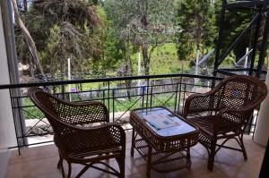 three chairs and a table on a balcony with a view at ARYASREE homestay in Kodaikānāl