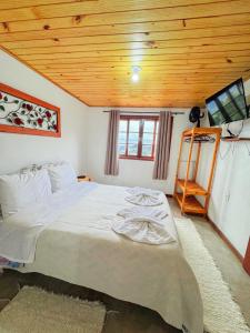 a bedroom with a large bed with a wooden ceiling at Chalés Cerejeira in Visconde De Maua +58 photos