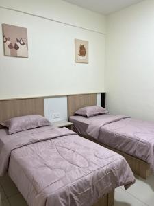 two beds in a room with purple blankets at Highland Chill Retreat in Tanah Rata