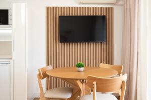 une table et des chaises avec une télévision sur un mur dans l'établissement Alsol Don Palomón, à Playa del Ingles