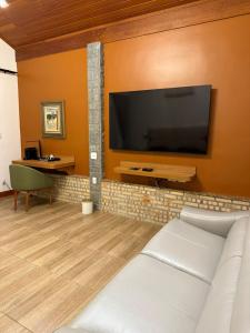 a living room with a large flat screen tv on a wall at Pequena Suíça Hotel Boutique in Chácara