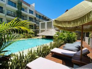 a swimming pool with an umbrella and chairs next to a building at Tulum City Apartments Bakal C in Tulum