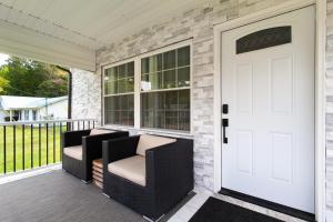 a porch with two chairs and a white door at Cozy Corner Spacious Area Outdoor Lounges in Knoxville