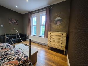 a bedroom with a bed and a dresser and a mirror at Walk from East Croydon Train Station in South Norwood