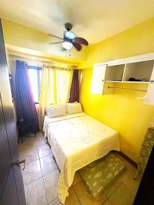a yellow bedroom with a bed and a ceiling fan at Condo 2Bedroom near Session with Free Own Parking in Baguio