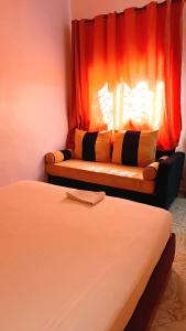 a room with two beds and a window with a couch at Dar abd essalam in Moulay Yacoub