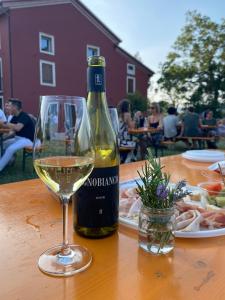 a bottle of white wine and a glass on a table at MASARI ALLA CASA ROSSA Vineyard guest house in Brogliano