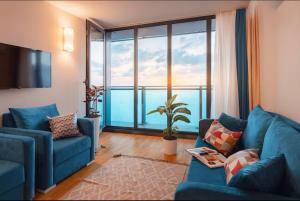 a living room with a blue couch and a large window at PANORAMA Luxury Hotel Batumi in Batumi