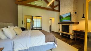 a bedroom with a large bed and a fireplace at Terrace Chalés in Monte Verde