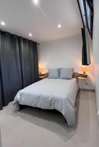 Un dormitorio con una cama blanca y cortinas negras. en Logement neuf au centre de Martigues avec parking, en Martigues