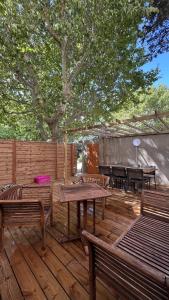 una terraza de madera con bancos, mesas y un árbol en Logement neuf au centre de Martigues avec parking, en Martigues