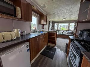 a small kitchen with a sink and a refrigerator at Superb 8 Berth Caravan At Highfield Grange Ref 26706Wr in Clacton-on-Sea