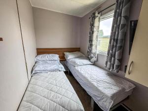 two beds in a small room with a window at Superb 8 Berth Caravan At Highfield Grange Ref 26706Wr in Clacton-on-Sea +14 photos