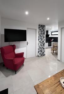 sala de estar con silla roja y TV de pantalla plana en Martigues centre logement neuf avec parking, en Martigues
