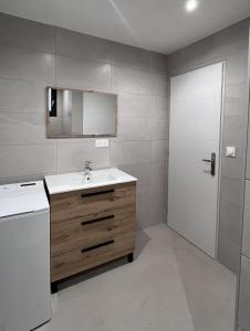 baño con lavabo, espejo y puerta en Martigues centre logement neuf avec parking, en Martigues