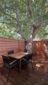 una mesa de madera y sillas en una terraza con un árbol en Martigues centre logement neuf avec parking, en Martigues