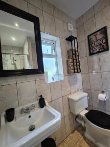 a bathroom with a sink and a toilet and a mirror at Walk from East Croydon Train Station in South Norwood