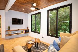 ein Wohnzimmer mit einem Sofa, einem TV und Fenstern in der Unterkunft Casa Pura Vida Manuel Antonio in Manuel Antonio