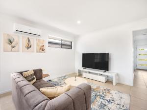 un salon avec un canapé et une télévision à écran plat dans l'établissement Bright Serenity Family Comfort near Parks and Shops, à Marsden