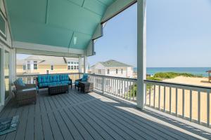a porch with two chairs and a couch on it at Salty Sunrise - K1224 in Whalebone