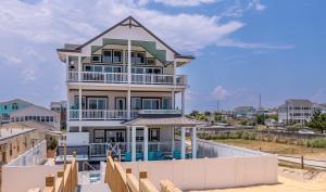a large house on the beach with a fence at Salty Sunrise - K1224 in Whalebone