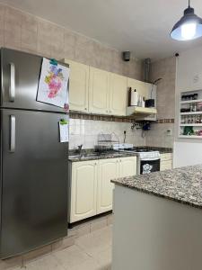 una cocina con nevera de acero inoxidable y armarios blancos en Departamento campitelli, en Santiago del Estero