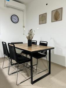 a dining room table with chairs and a clock on the wall at Departamento campitelli in Santiago del Estero +4 photos