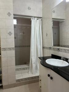 Un baño con ducha y lavabo blanco. en Departamento campitelli, en Santiago del Estero