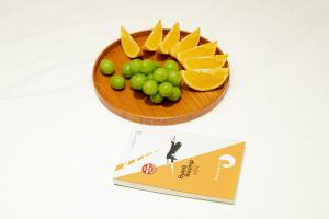 eine Obstschale mit Orangen und Trauben neben einem Buch in der Unterkunft MYAN Villa Phòng nghỉ 3 Vinhomes Ocean Park 3 in Ðình Loan + 22 Fotos