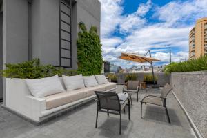 a patio with a couch and chairs and an umbrella at Capitalia Palacio Polanco in Mexico City