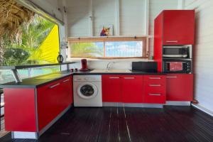 a kitchen with red cabinets and a washing machine at Bungalow la paillote in Le François