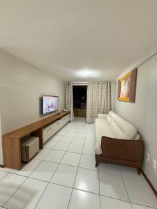 een woonkamer met een bank en een tv bij Apartamento em Maceió in Maceió