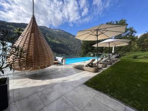 a pool with chairs and umbrellas in a yard at Boutique Apartment Sonnenhang - incl InfinityPOOL in Fliess