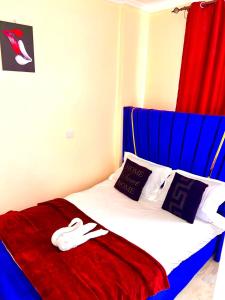 ein Bett mit einer roten Decke und einem Paar Schuhe darauf in der Unterkunft Twilight Tower in Eldoret + 6 Fotos