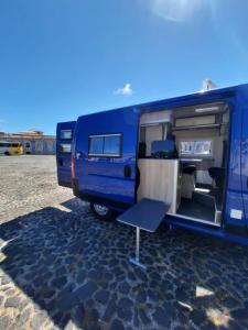 a blue rv parked in a parking lot with its door open at Caravana Poço Bispo in Lisbon