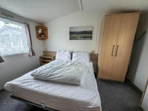 Un dormitorio con una cama y un armario de madera. en 6 Berth Staycation Caravan Nearby Clacton-On-Sea In Essex Ref 26254E, en Clacton-on-Sea 15 fotos más