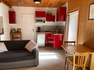 a living room with a couch and a kitchen with red cabinets at Studio Serre Chevalier Briancon in Briançon