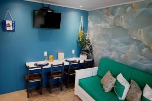 a dining room with a table and a green couch at Apto Climatizado com varanda próximo a praia in Itapema