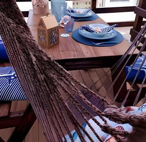 a table with a hammock and plates on it at Apto Climatizado com varanda próximo a praia in Itapema