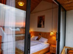 Un dormitorio con una cama y una puerta de cristal. en Muhazi Dolce Vita Ecolodge, 