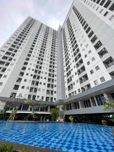 a large building with a blue pool in front of it at The Avenue Parkland Serpong by Ngeroomin in Babakan