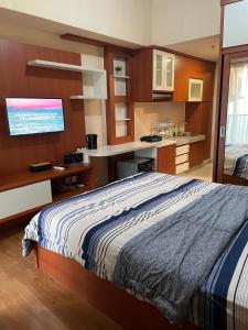 a bedroom with a bed and a kitchen at The Avenue Parkland Serpong by Ngeroomin in Babakan